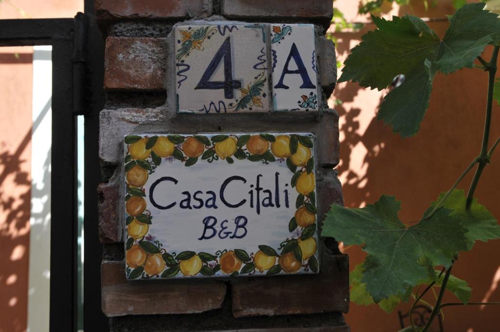 una señal en el costado de una pared de ladrillo en Casa Cifali, en Taormina