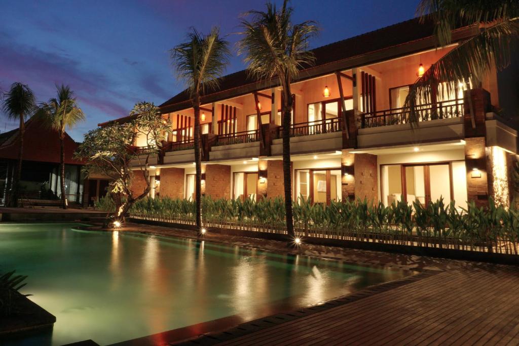 a hotel with a swimming pool in front of a building at Arena Living in Sanur