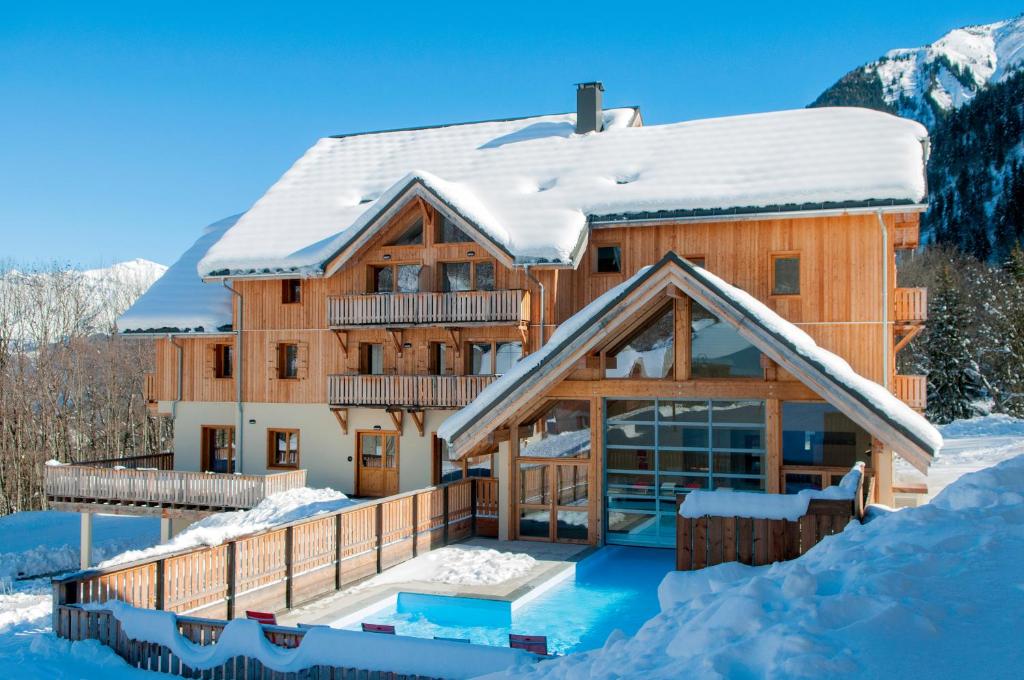 Casa de madera grande con techo cubierto de nieve en Goélia Les Chalets de Belledonne en Saint-Colomban-des-Villards