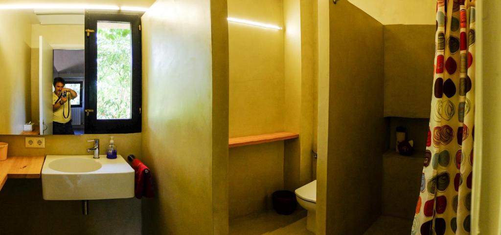 un hombre tomando una foto de un baño con lavabo en Ca L'Olier, en Montblanquet