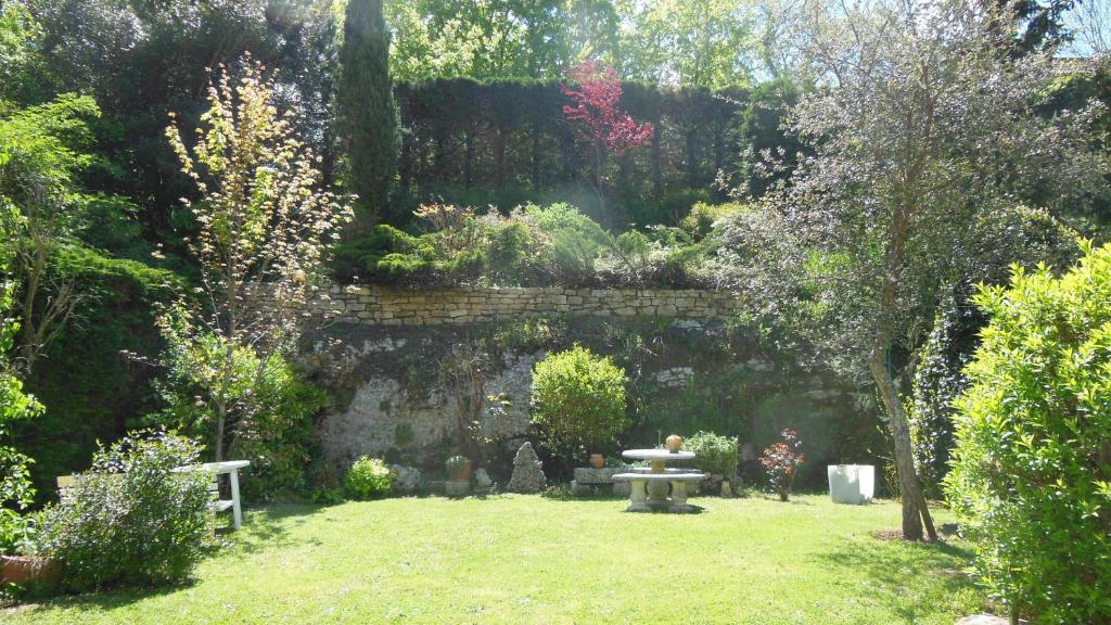 a garden with a stone wall and a picnic table at Hôtel restaurant HENRY in Puy-lʼÉvêque