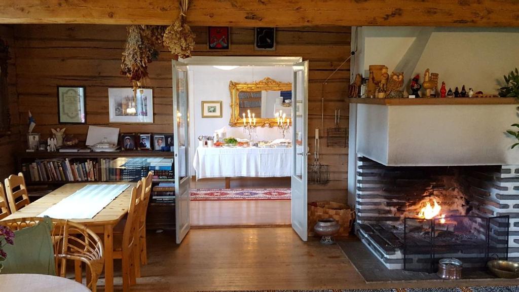 a room with a fireplace and a dining room with a table at Lomatila Ollila Farm Stay in Kerimäki