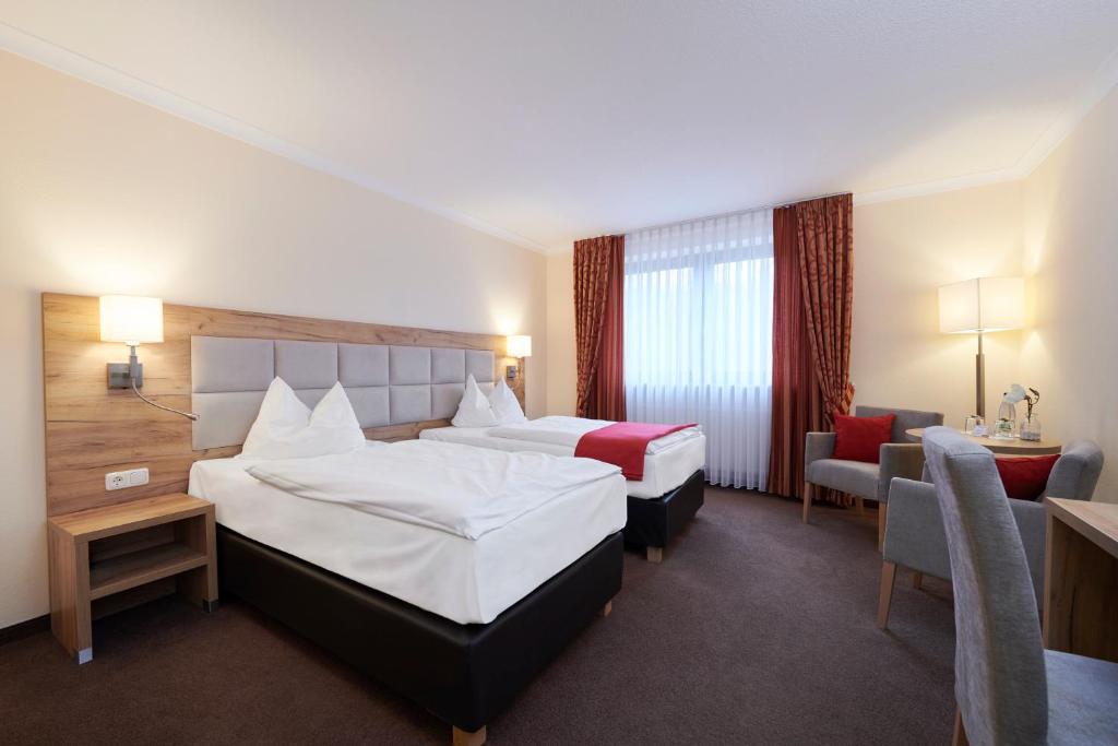 a hotel room with two beds and a chair at Korbstadthotel Krone in Lichtenfels