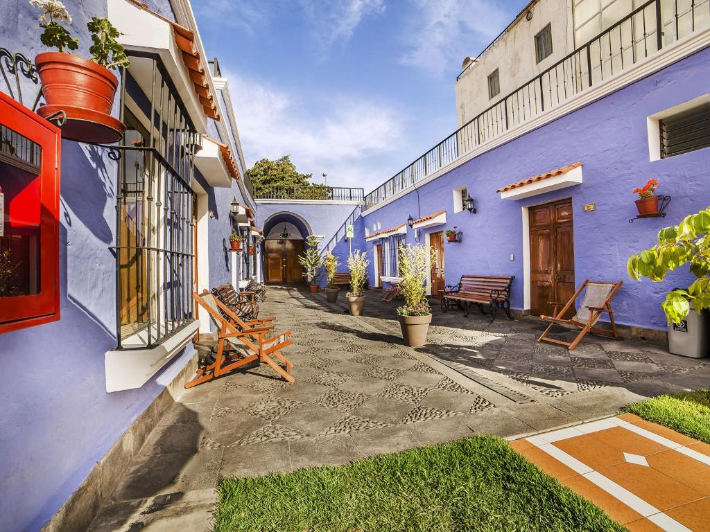 dziedziniec niebieskiego budynku z krzesłami i stołami w obiekcie Las Torres de Ugarte w mieście Arequipa