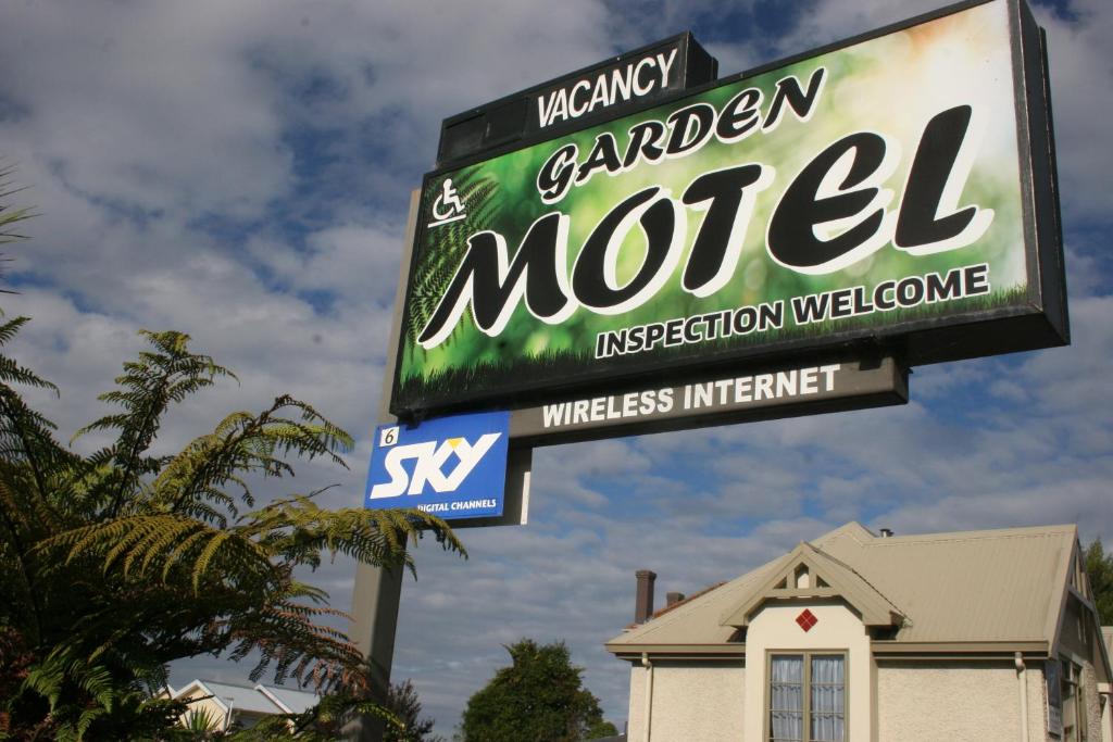 un cartel para un motel en el jardín frente a una casa en Garden Motel, en Dunedin