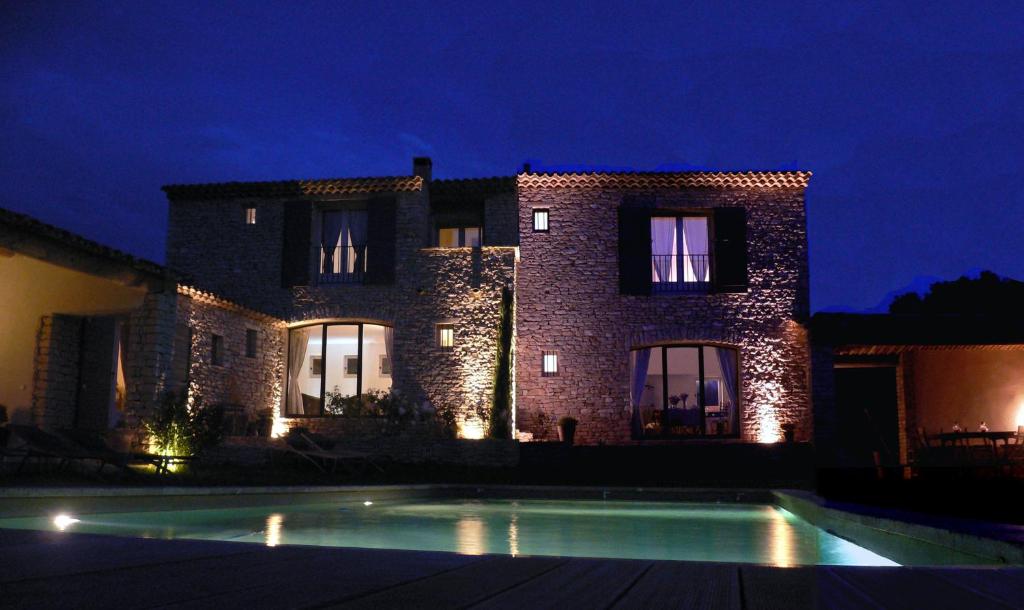 une maison avec une piscine en face de celle-ci la nuit dans l'établissement Les Terrasses - Gordes, à Gordes