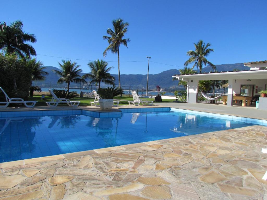 uma piscina com um pátio de pedra e uma casa em Hotel Guarda Mor em São Sebastião