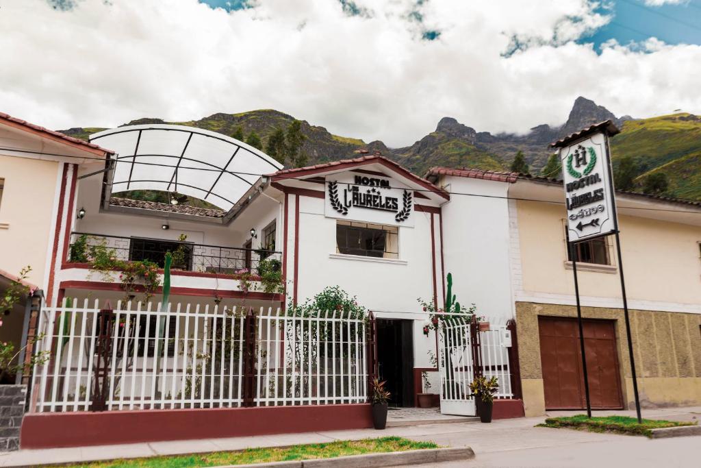 una casa blanca con una puerta y montañas al fondo en Hotel Los Laureles, en Calca