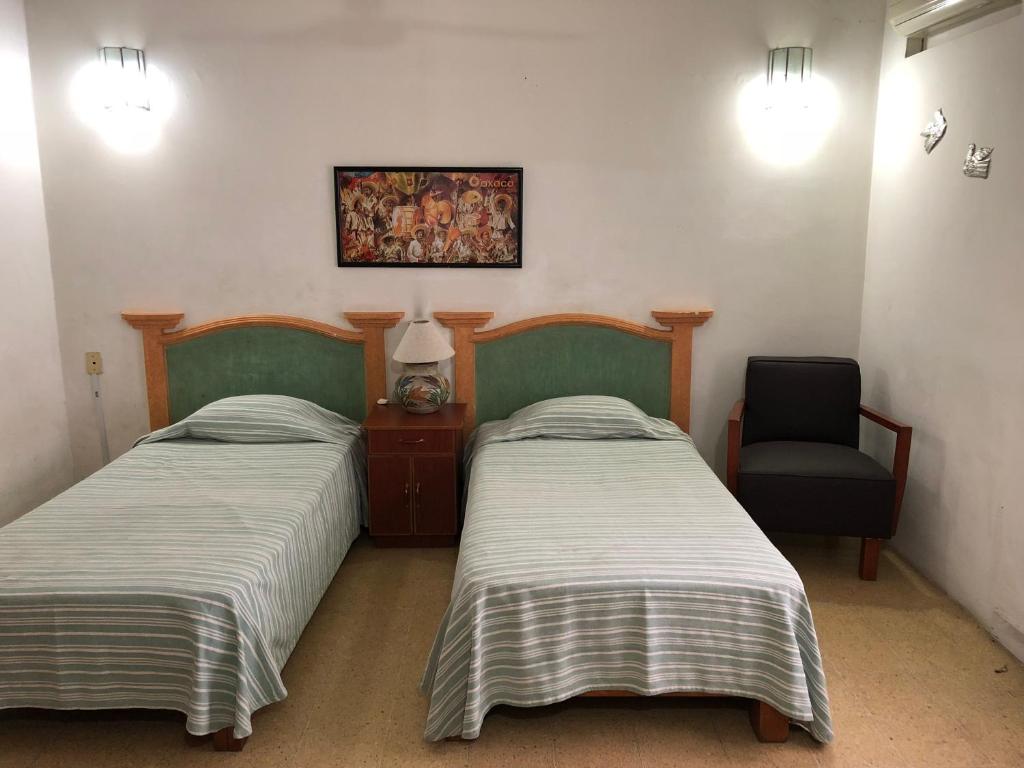 a bedroom with two beds and a chair and a picture at Meson del Penasco in Oaxaca City