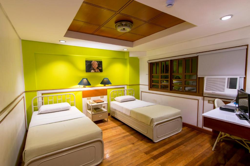 two beds in a room with a desk and a computer at The Manor Hotel in Davao City