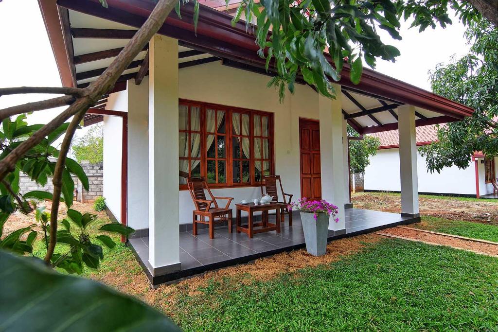 Casa con porche con mesa y sillas en Dambulla Hills Resort, en Dambulla