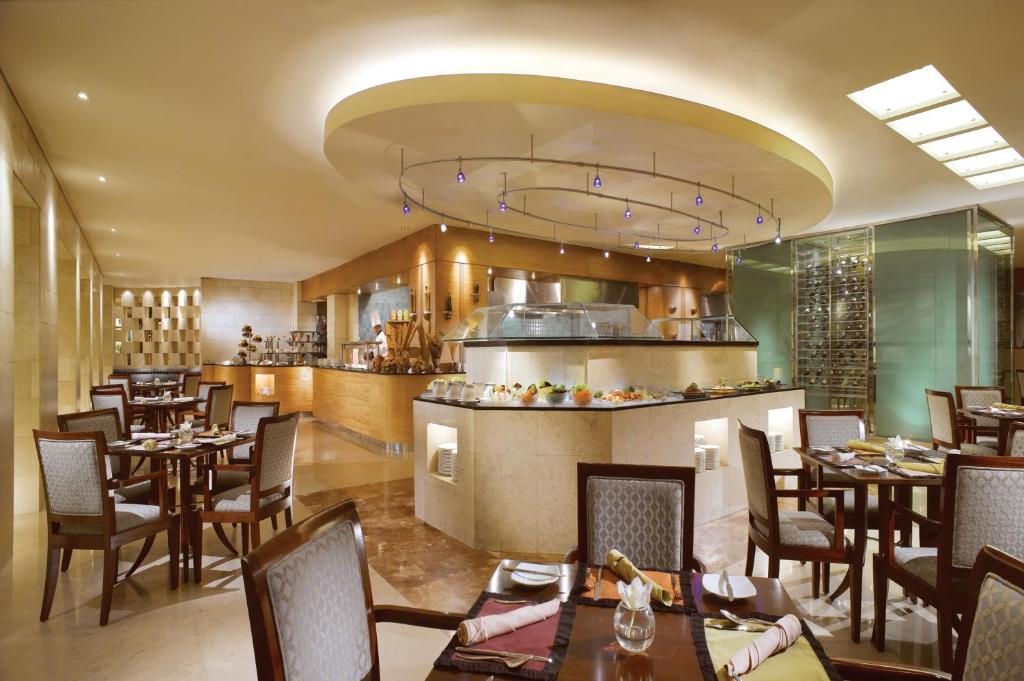 a restaurant with tables and chairs and a kitchen at Hotel Borobudur Jakarta in Jakarta