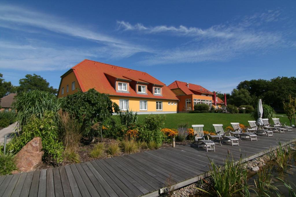 un grupo de sillas sentadas en una terraza de madera frente a una casa en Hotel & Restaurant Zum Kap Arkona en Putgarten