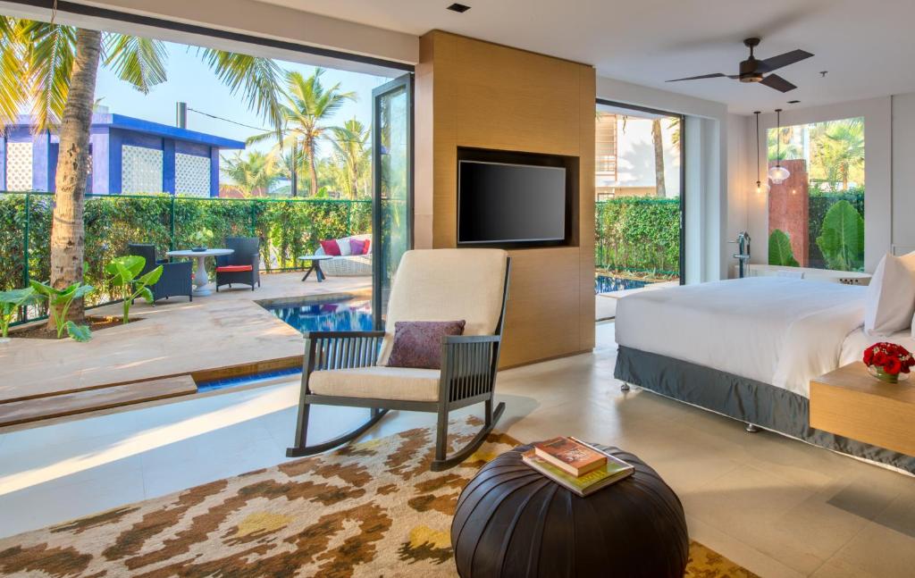 a bedroom with a bed and a tv and a patio at Azaya Beach Resort Goa in Benaulim