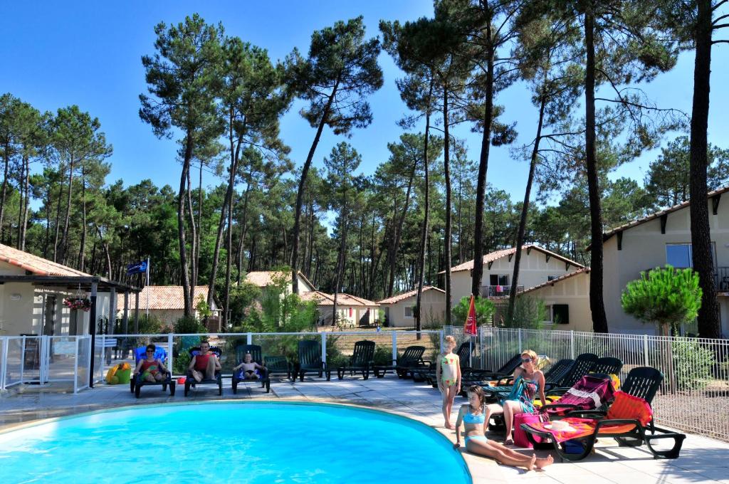 um grupo de pessoas sentadas ao redor de uma piscina em Résidence Goélia Les Demeures du Lac em Casteljaloux