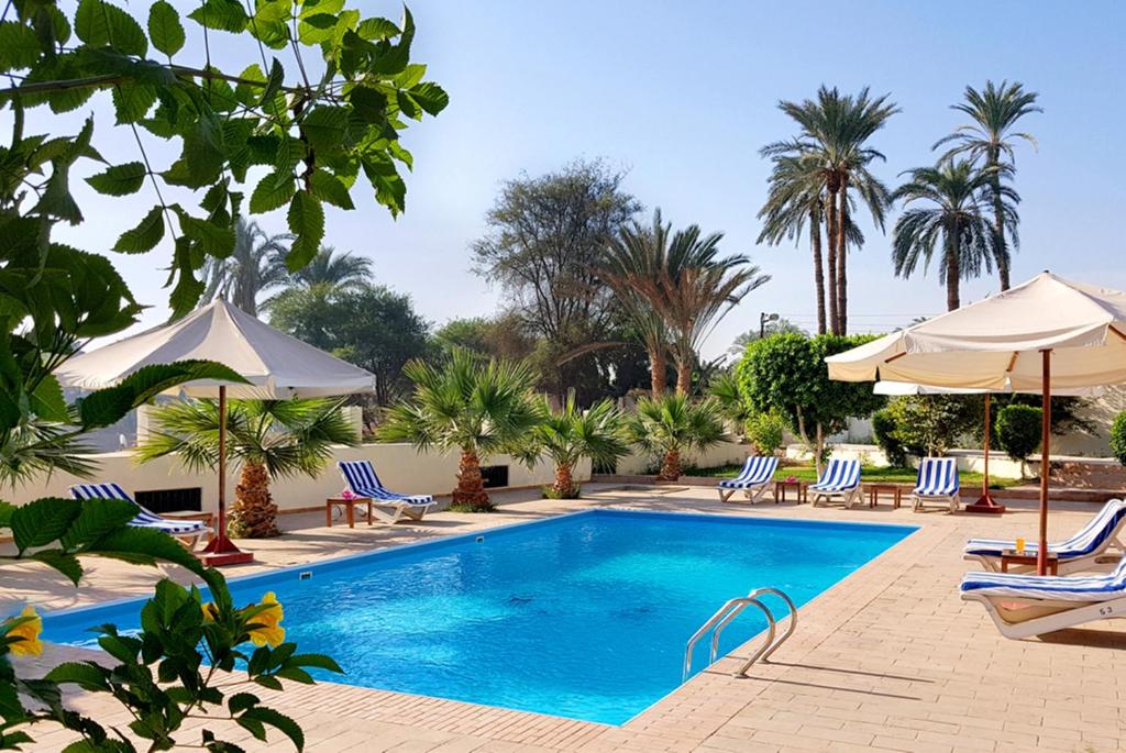 una piscina en un complejo con sillas y sombrillas en Hotel Sheherazade Luxor, en Luxor