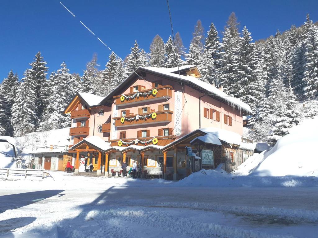 ein großes Gebäude im Schnee mit schneebedeckten Bäumen in der Unterkunft Hotel La Roccia in Passo del Tonale