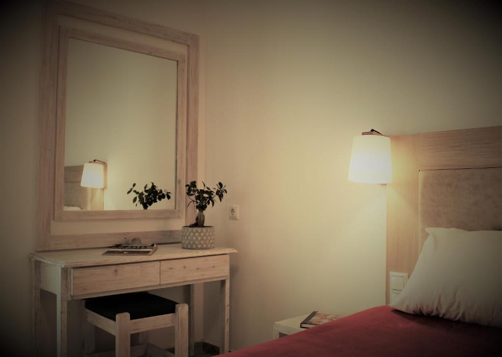 Schlafzimmer mit einem Schreibtisch, einem Spiegel und einem Bett in der Unterkunft Sappho Plomari in Plomari