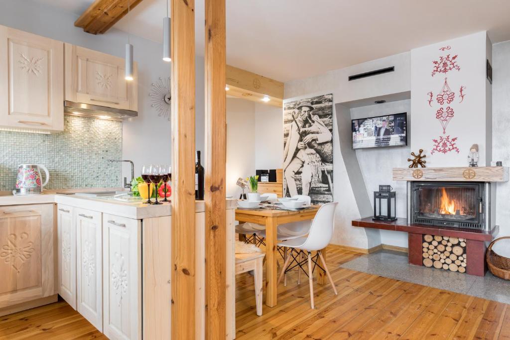 a kitchen and dining room with a table and a fireplace at Apartament Marmurki Zakopane in Zakopane