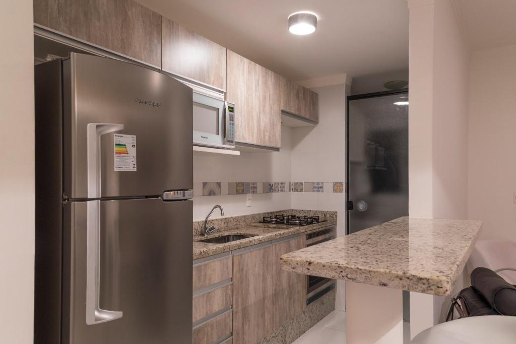 uma cozinha com um frigorífico de aço inoxidável e um balcão em Apartamento Moderno Poços de Caldas em Poços de Caldas