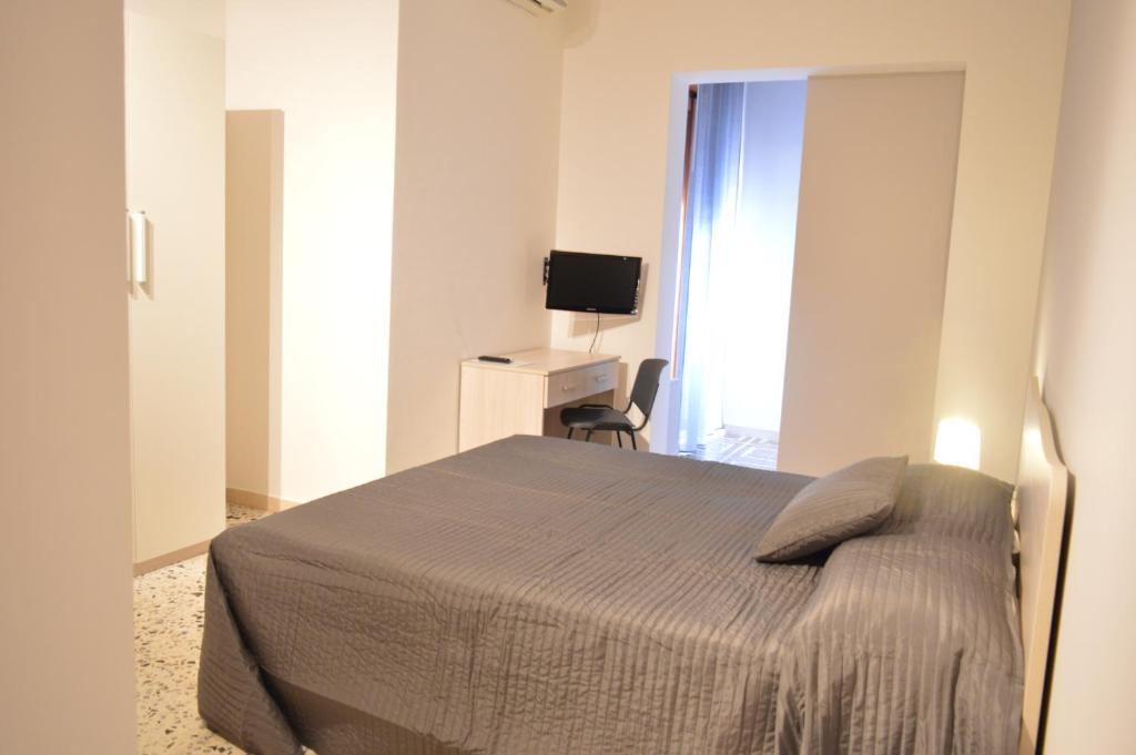 um quarto com uma cama, uma escrivaninha e uma televisão em B&B Scalea Rooms em Scalea