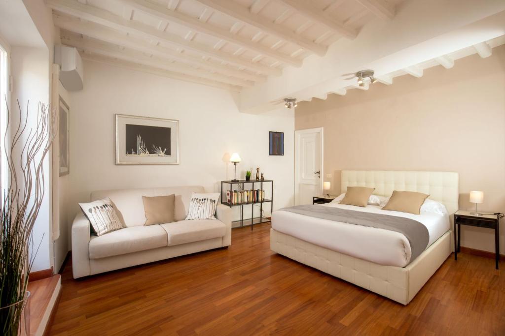 a white bedroom with a bed and a couch at Cozy Studio Parlamento in Rome