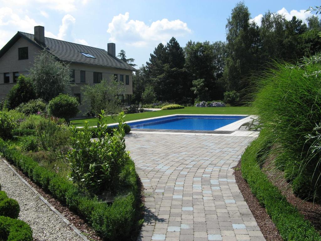 
a garden area with a stone wall and a blue and white house at B&B Au Grenier in Ghent
