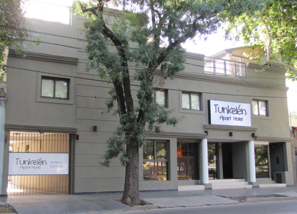 Tunkelén Apart Hotel في ميندوزا: مبنى امامه شجرة