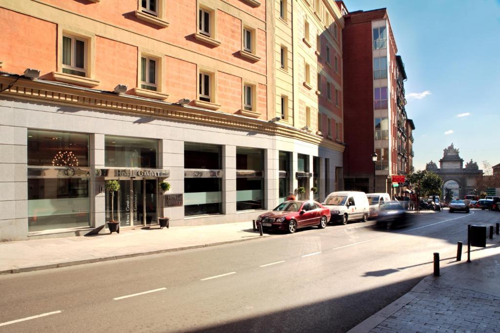 a red car driving down a city street with buildings at Porcel Ganivet in Madrid