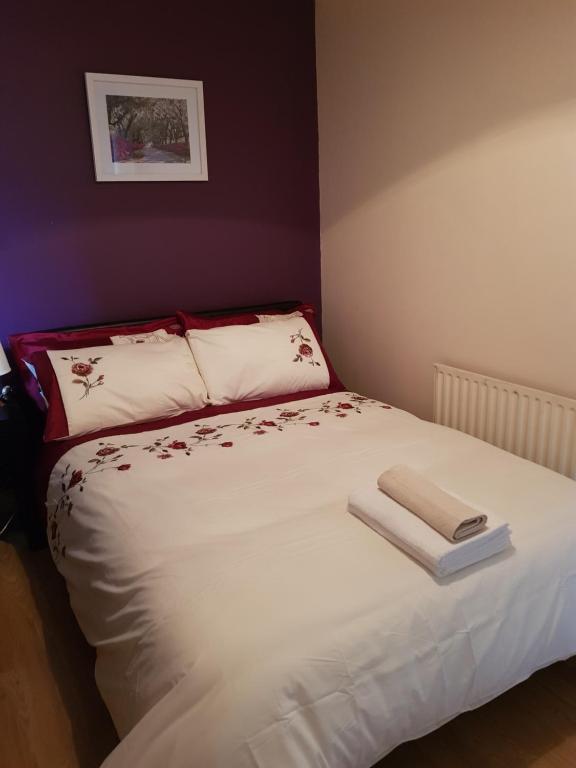 Un dormitorio con una cama blanca con un libro. en Ashemere Lodge en Clondalkin 