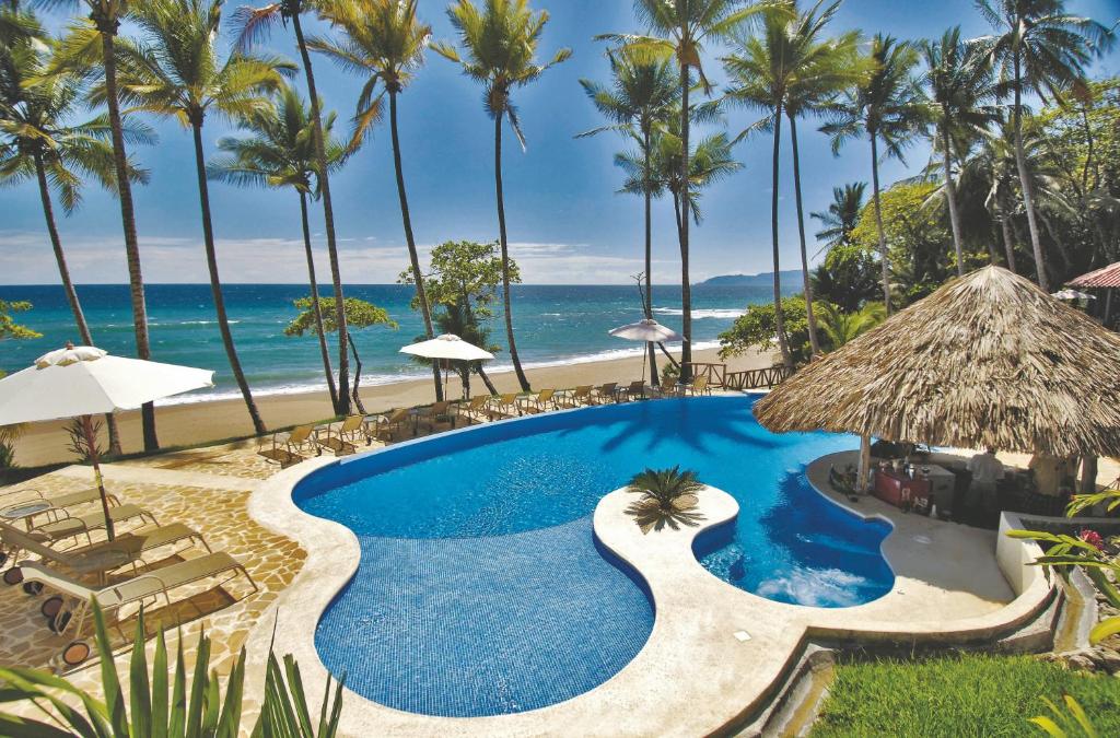 a pool at the beach with palm trees and the ocean at Tango Mar Beachfront Boutique Hotel & Villas in Tambor