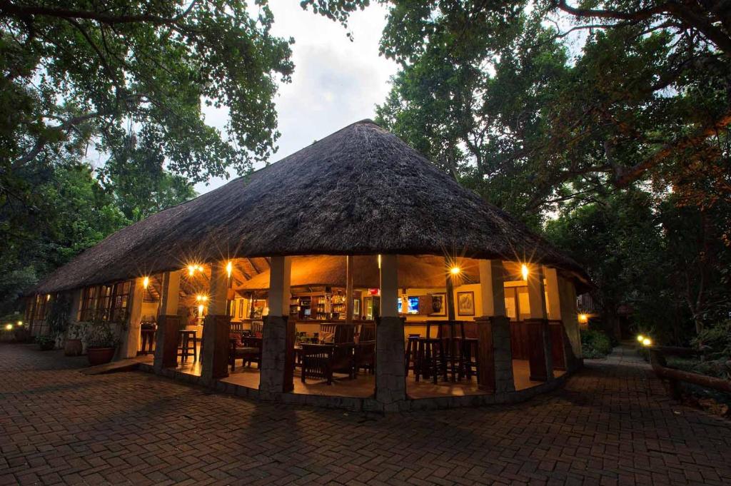 um edifício com telhado de palha com mesas e cadeiras em Island Safari Lodge em Maun