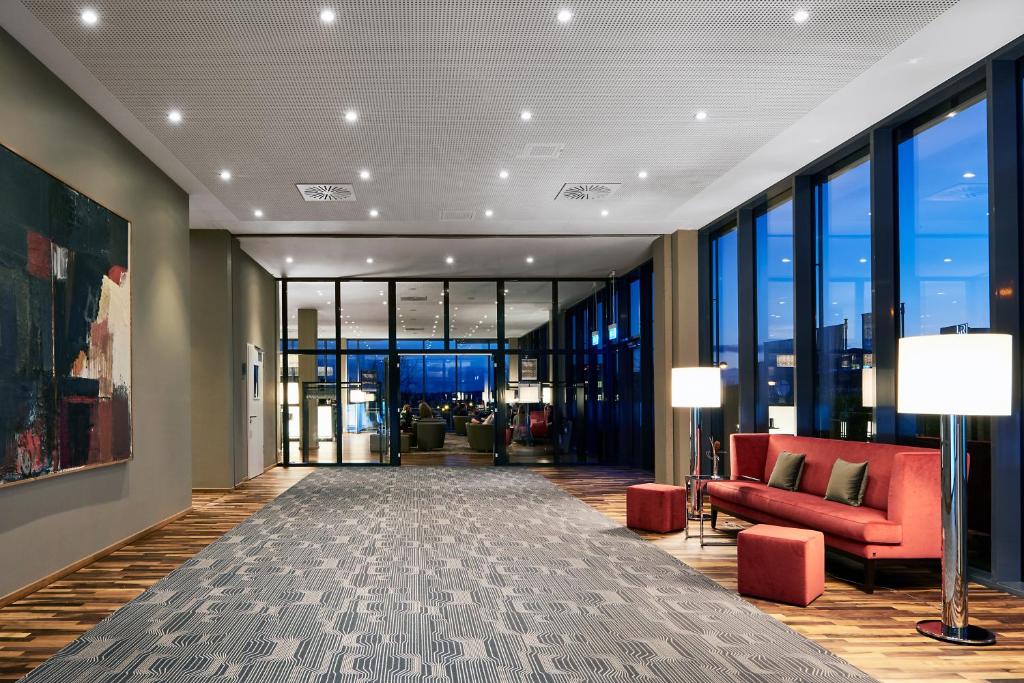 an office lobby with red furniture and large windows at LÉGÈRE HOTEL Luxembourg in Luxembourg