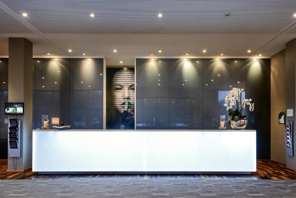 a lobby with a white counter with a poster on the wall at LÉGÈRE HOTEL Luxembourg in Luxembourg