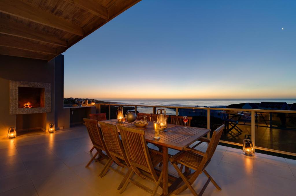a dining table on a balcony with a view of the ocean at Stanford's Cove Villas in Gansbaai