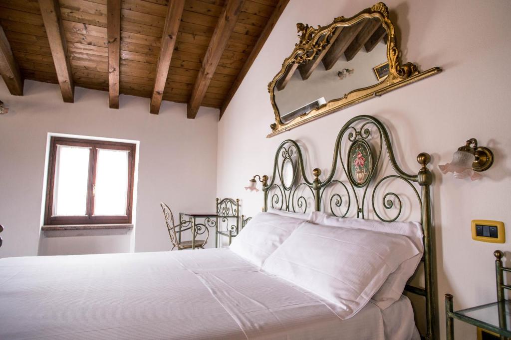 Schlafzimmer mit einem Bett und einem Wandspiegel in der Unterkunft Hotel e Locanda La Bastia in Valeggio sul Mincio