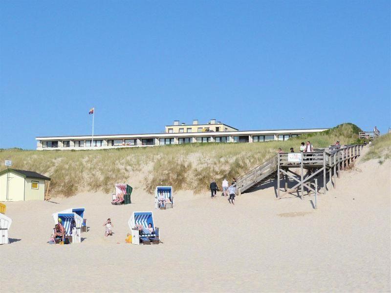 a beach with people on the sand and a pier at Duenenhof-App-31-32-Meerseite in Wenningstedt