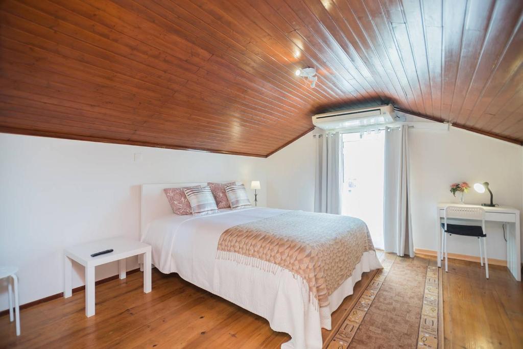 a bedroom with a large bed with a wooden ceiling at Lisbon Belém Guesthouse in Lisbon