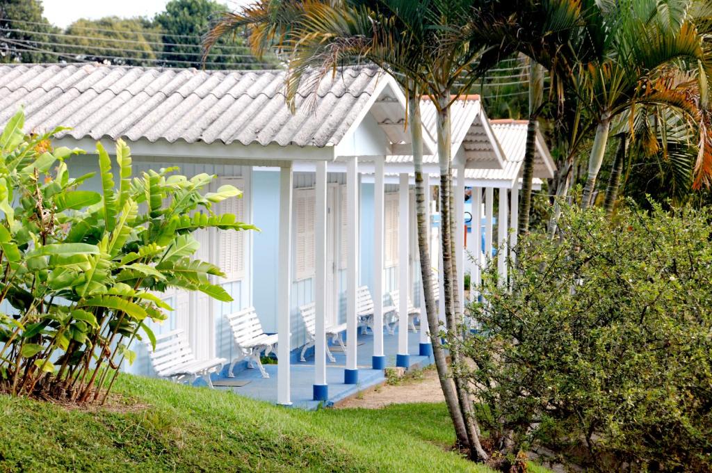 a building with chairs and palm trees in front of it at Big Valley Hotel Fazenda in Serra Negra