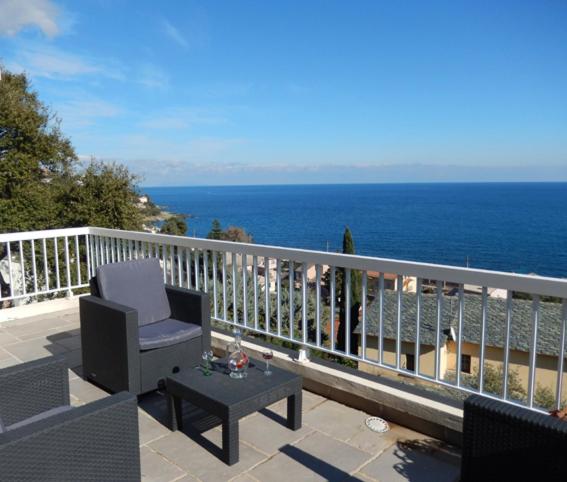 a balcony with a chair and a table and the ocean at Maison Oxalys in Bastia