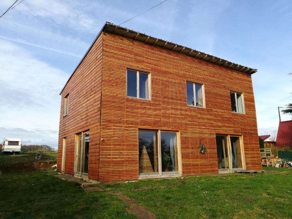 une grande maison en bois sur une pelouse dans l'établissement Maison ecologique en paille, à La Chapelle-Enchérie