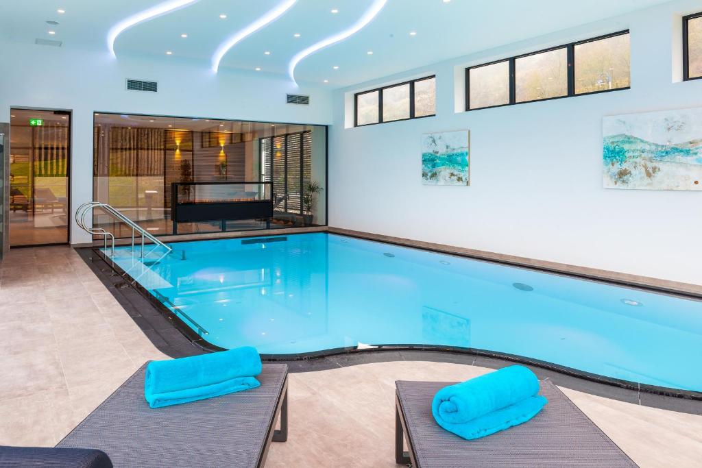 a large swimming pool with two blue chairs at Hotel Die Post Meerfeld in Meerfeld