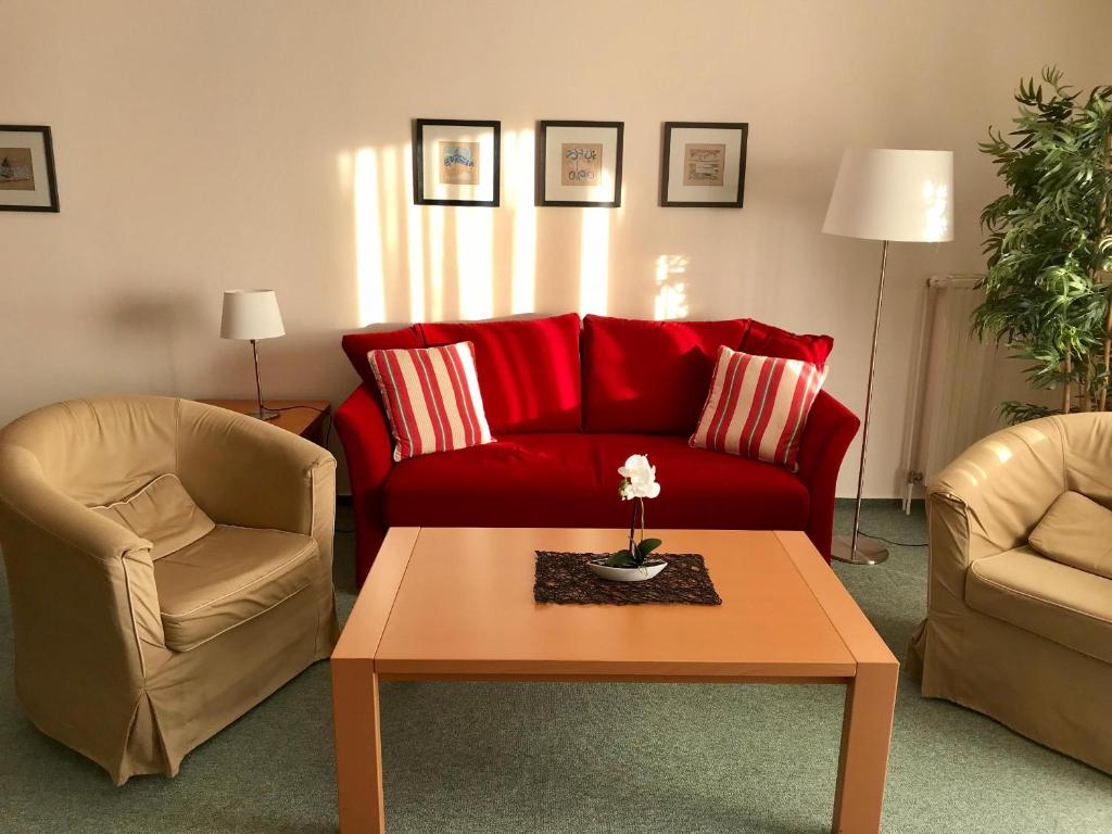 ein Wohnzimmer mit einem roten Sofa und 2 Stühlen in der Unterkunft Steiner Strandappartements Appartement 308 Süd- Landseite in Stein