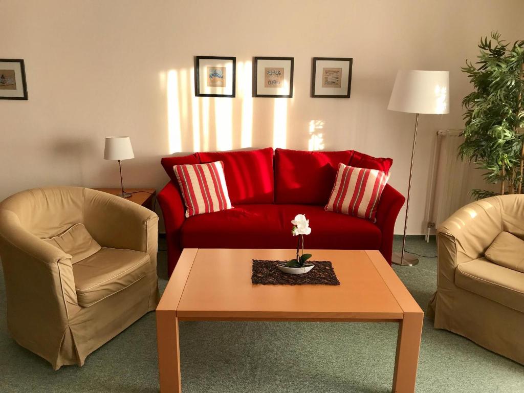 sala de estar con sofá rojo y 2 sillas en Steiner Strandappartements Appartement 308 Süd- Landseite, en Stein