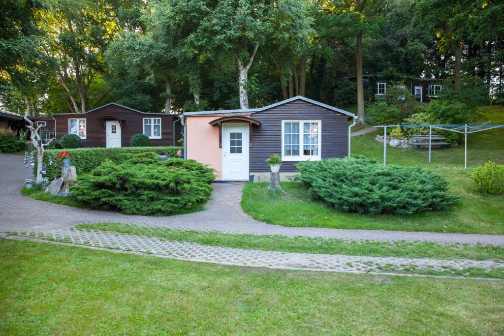 een klein huis met een witte deur in een tuin bij Ferienhausanlage Juhrs in Binz