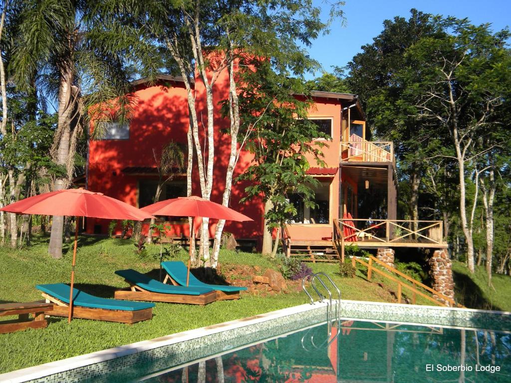 a house with umbrellas and chairs next to a pool at El Soberbio Lodge in El Soberbio