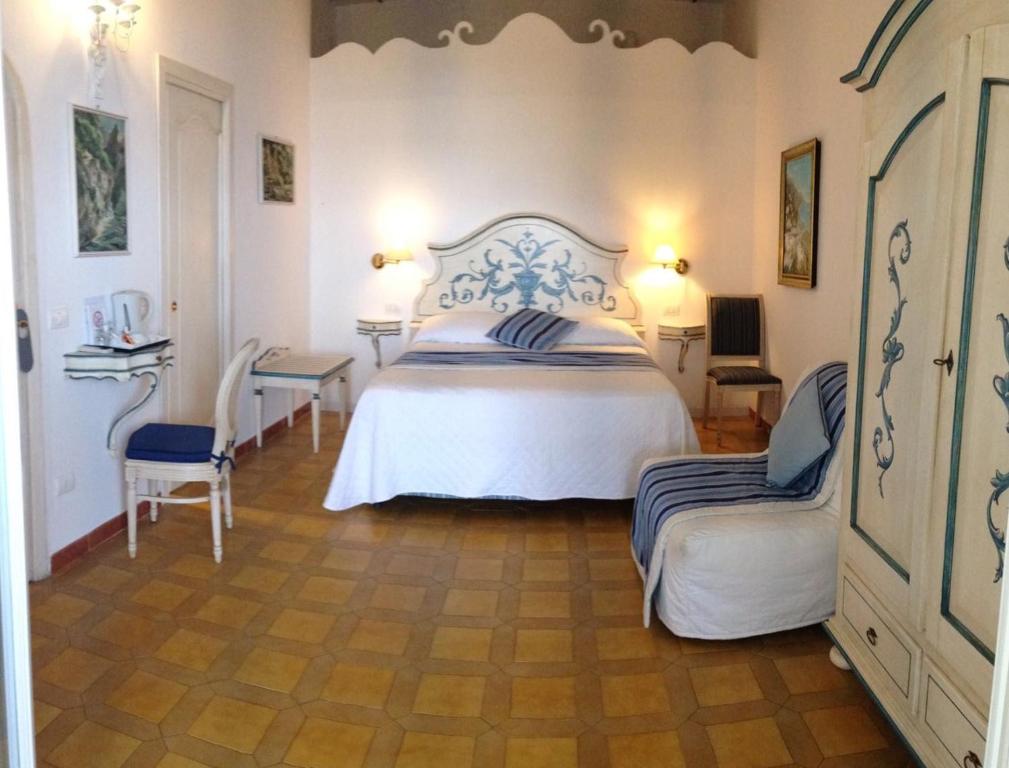a bedroom with a large white bed and two chairs at Hotel Villa Delle Palme in Positano in Positano