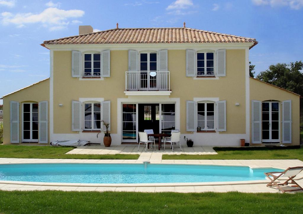 una casa con piscina frente a ella en Madame Vacances Les Villas de Fontenelles, en LʼAiguillon-sur-Vie