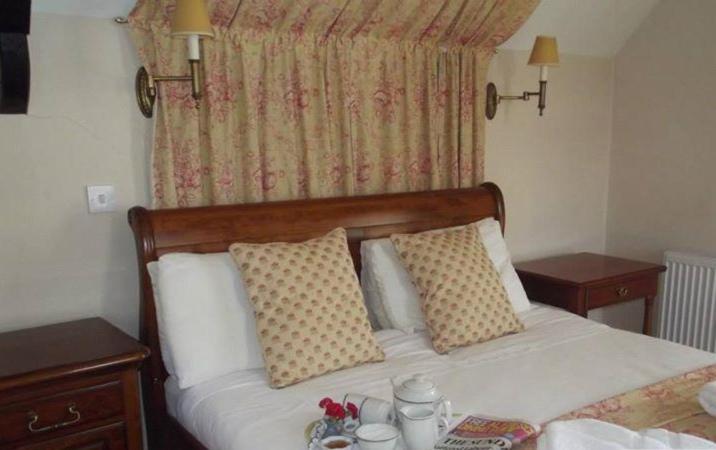 1 dormitorio con cama con almohadas y ventana en Meath Arms Country Inn en Aughrim