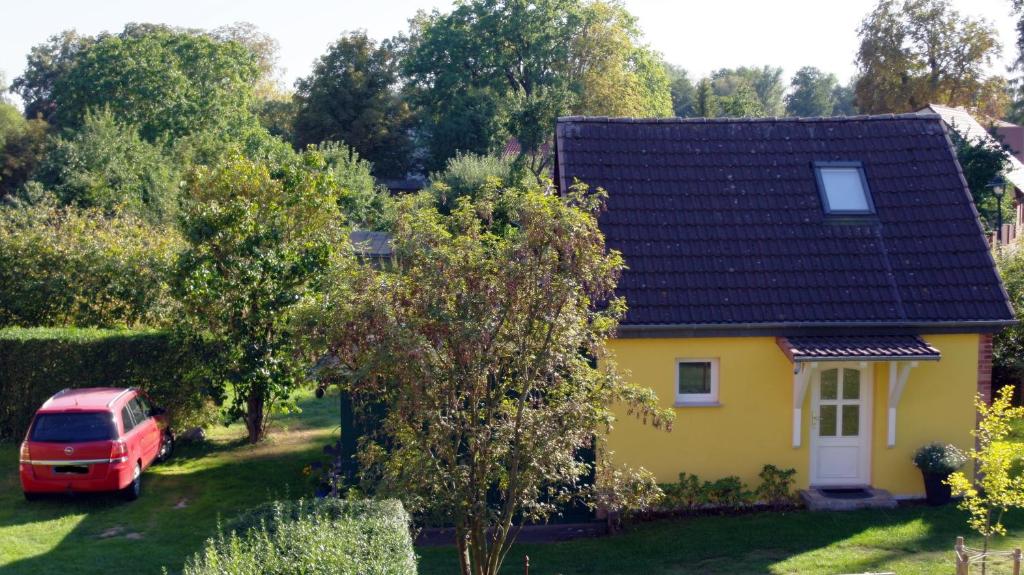 une maison jaune avec une camionnette rouge garée dans la cour dans l'établissement Gästehaus A+C Bovet, à Wesenberg